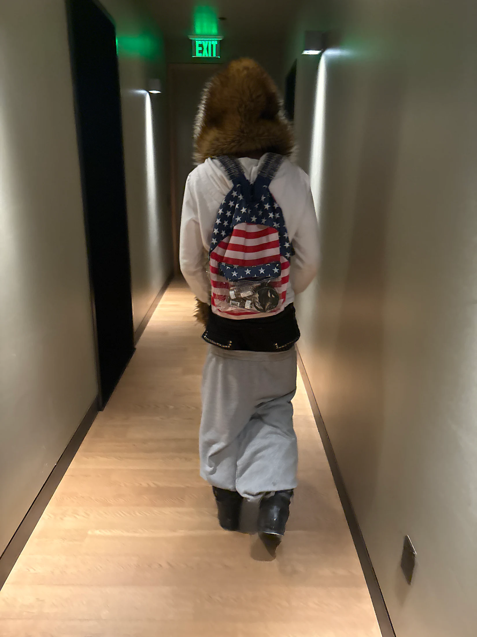 Model walking down a hallway wearing the Armor Backpack — American Flag.