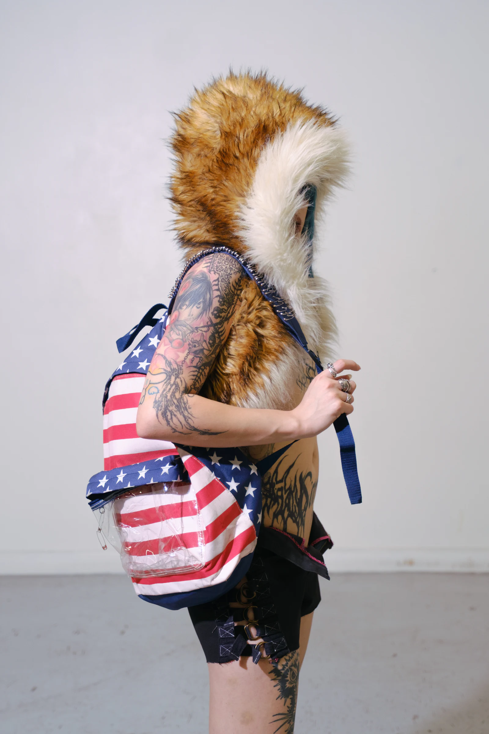 Side portrait of a tattooed model wearing the Armor Backpack — American Flag.