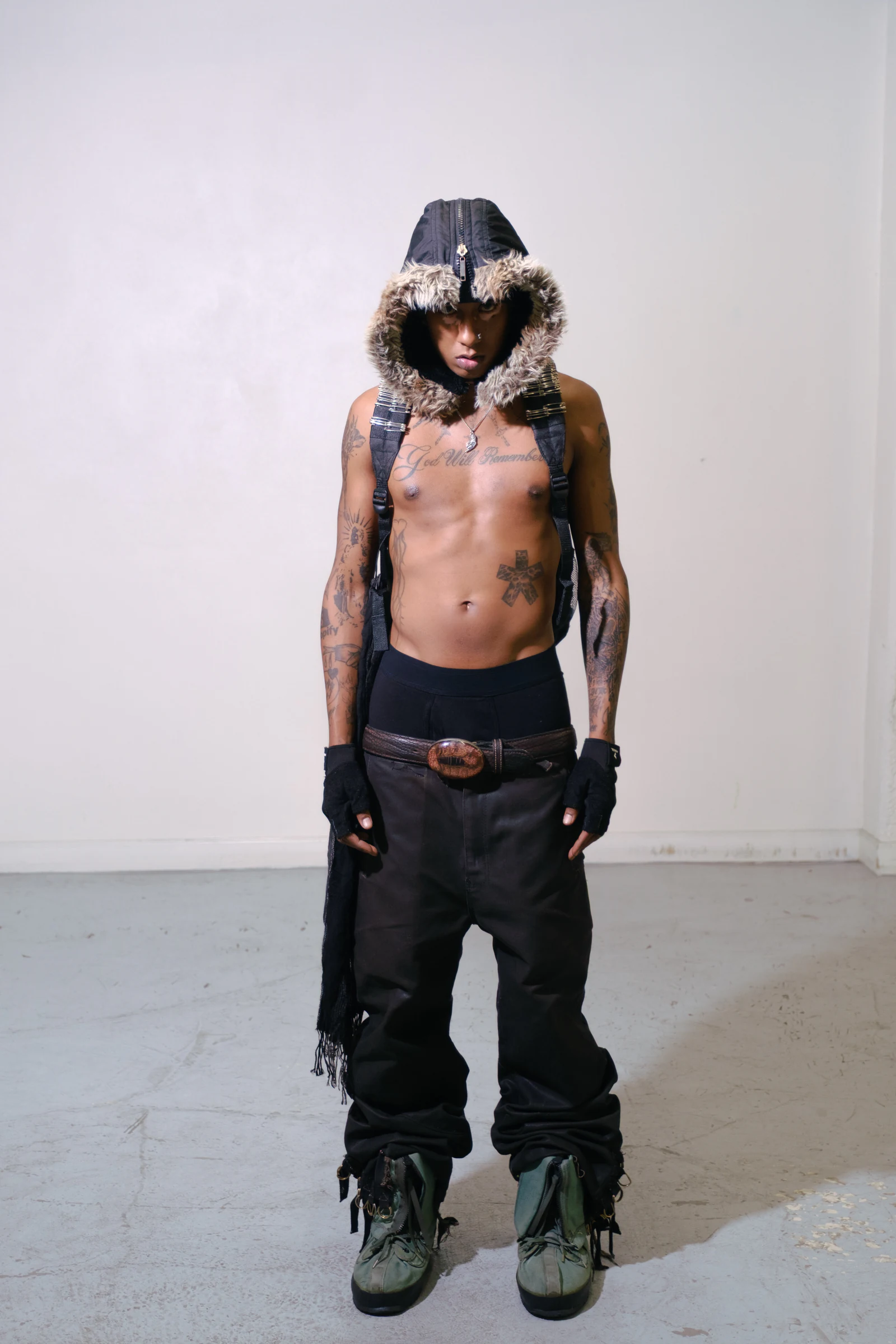 Model in waxed black pants wearing the Armor Backpack — Blackout in a studio.