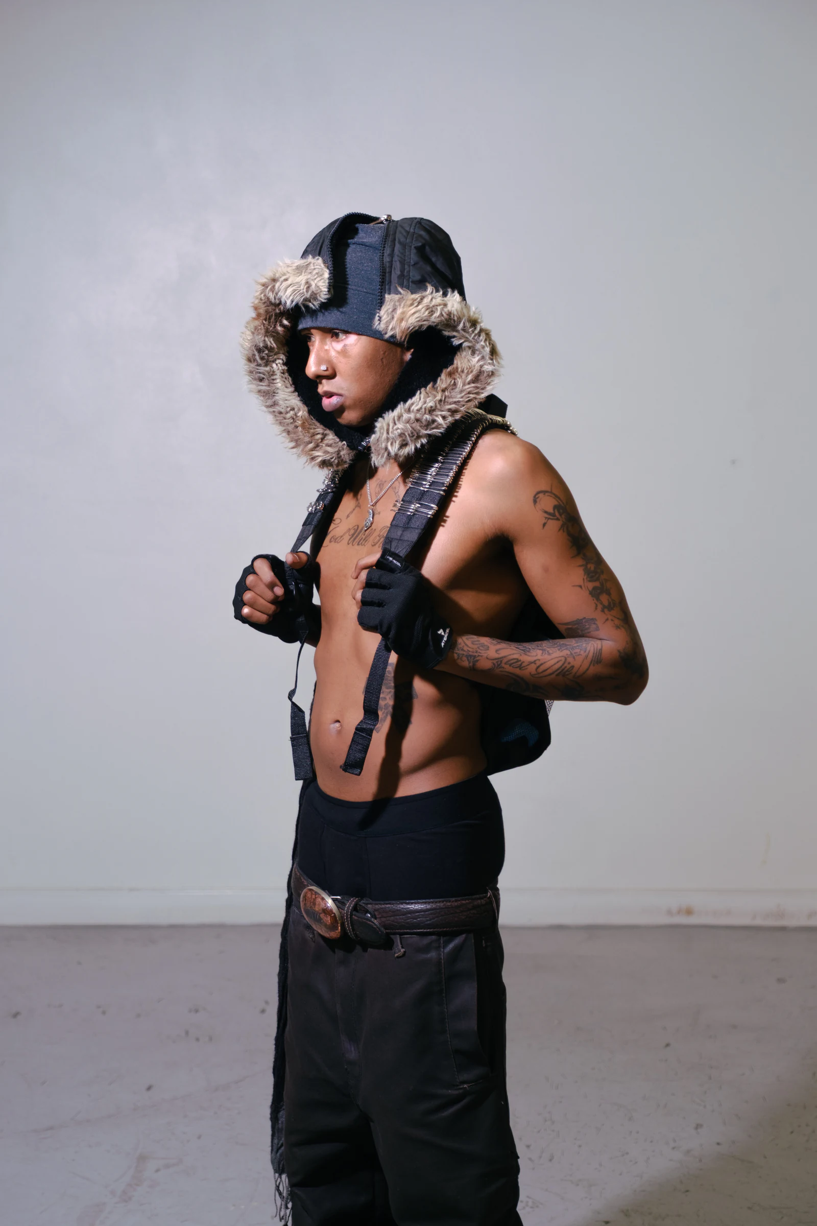 Side portrait of a model wearing the Armor Backpack — Blackout and waxed black pants.